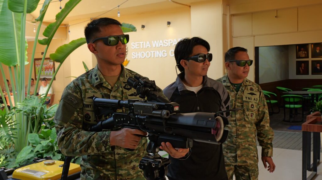 Lieutenant Colonel Infantry Denny Sopyan wearing protective goggles shoulders the EGI counter-UAV laser gun, with a Paspampres officer and an EGI engineer beside him